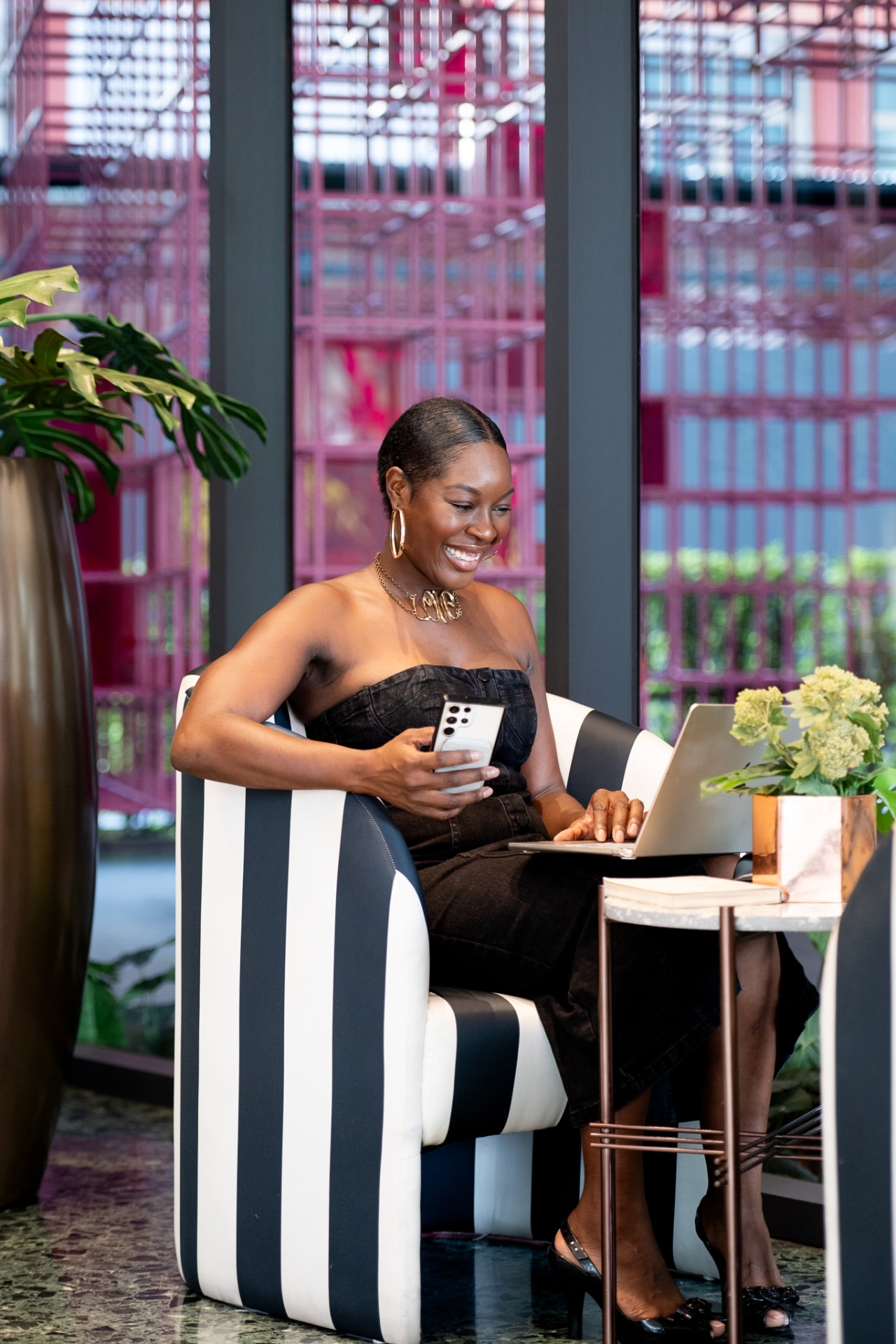 Issa smiling while working on a laptop in a striped armchair